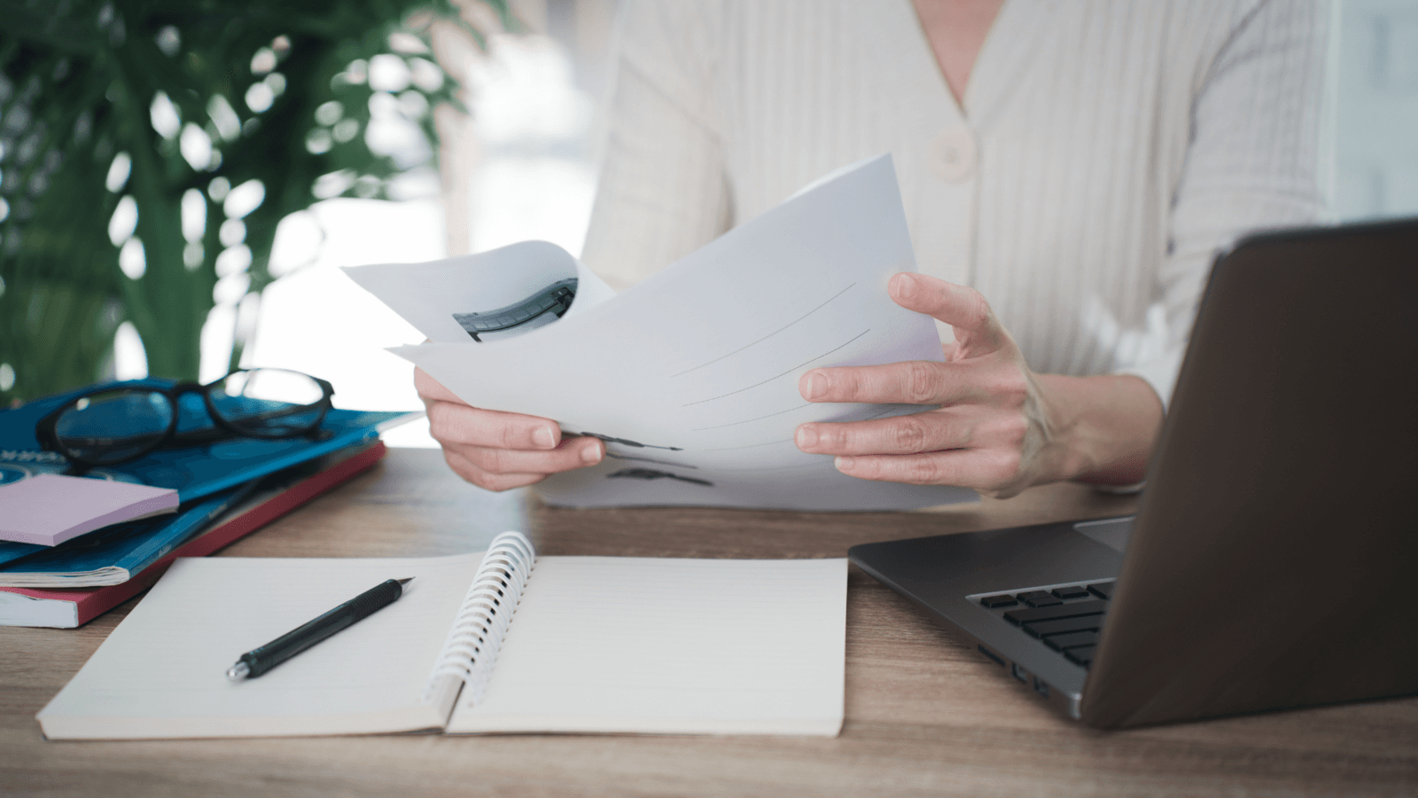 Reviewing documents at a desk beside a notebook and laptop